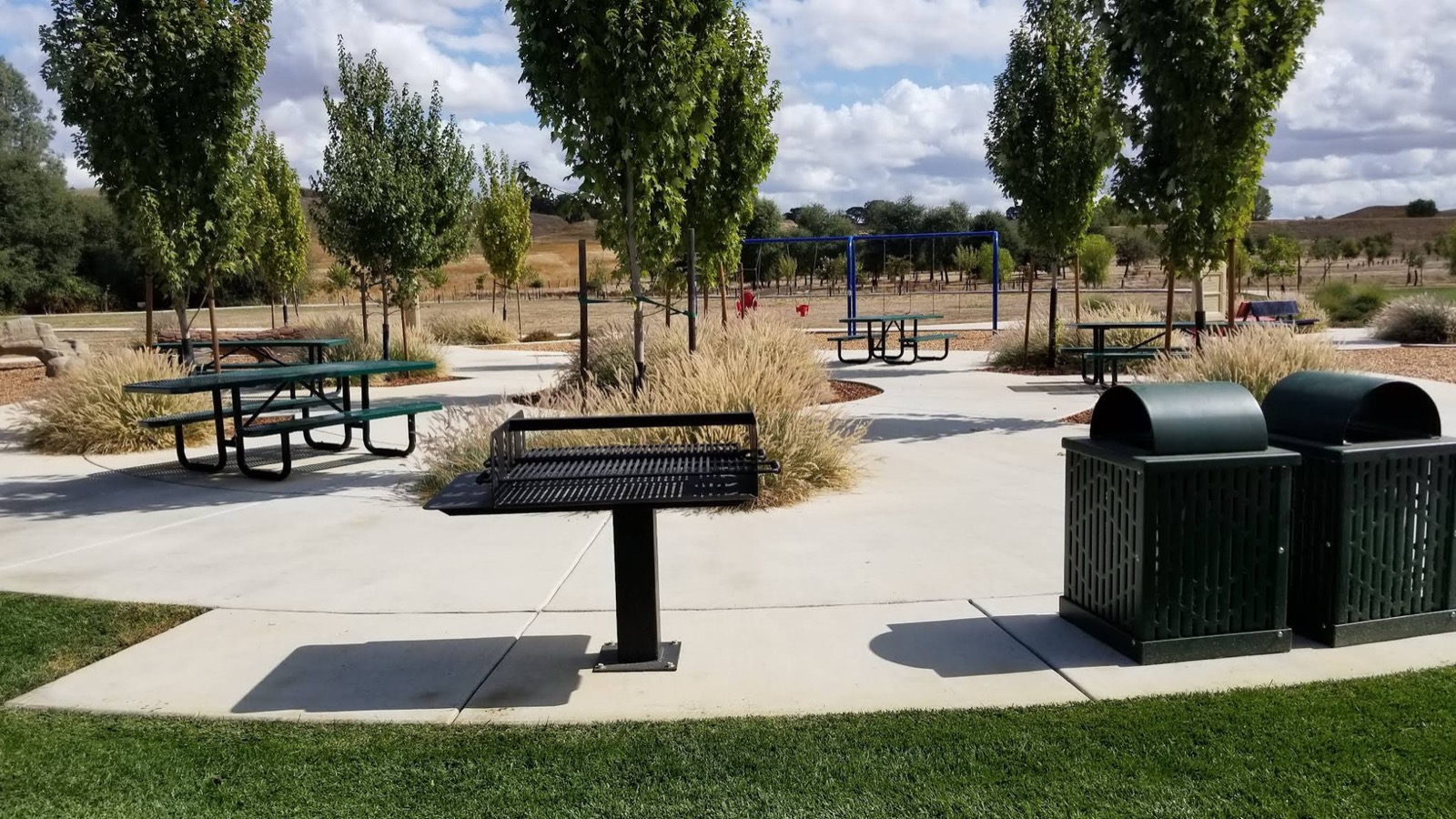 Picnic tables and a barbecue grill at The Greens Park
